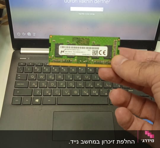 אדם מחזיק זיכרון RAM מול מחשב נייד
